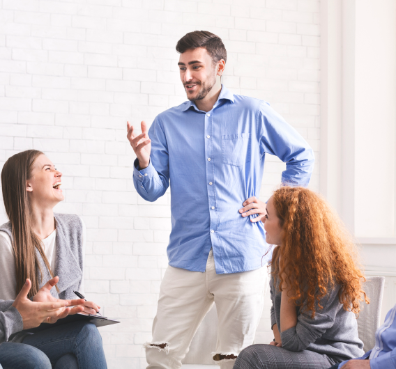 Cheerful Man Telling Jokes To Community Members At Group Meeting In Rehab